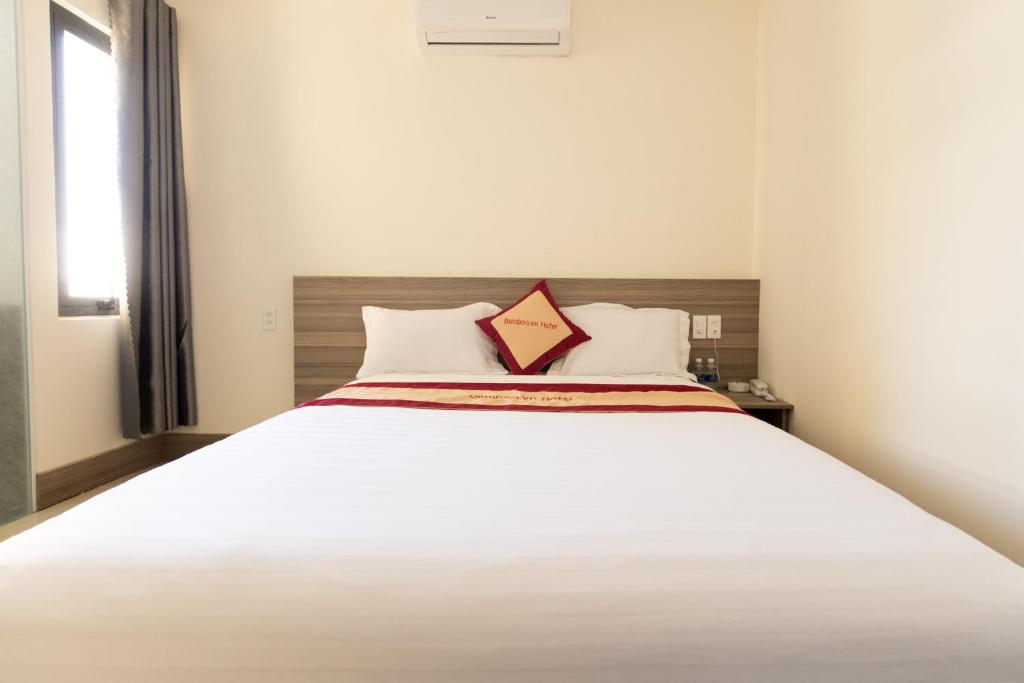 - une chambre avec un grand lit blanc et un oreiller orange dans l'établissement Bamboo Hotel, à Vung Tau
