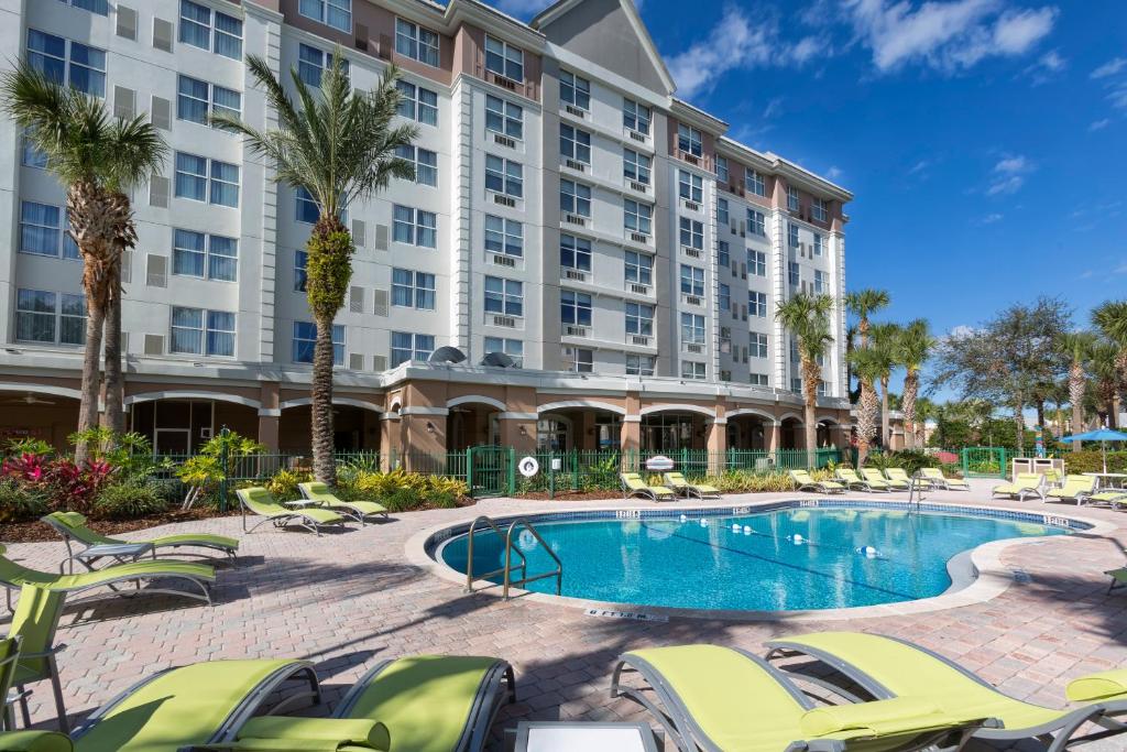 a hotel with a pool and chairs and a building at Holiday Inn Express & Suites S Lake Buena Vista by IHG in Kissimmee