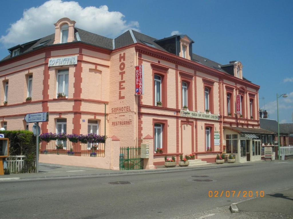 un grand bâtiment en briques rouges dans une rue de la ville dans l'établissement Logis - Hôtel et Restaurant Le Sofhotel, à Forges-les-Eaux