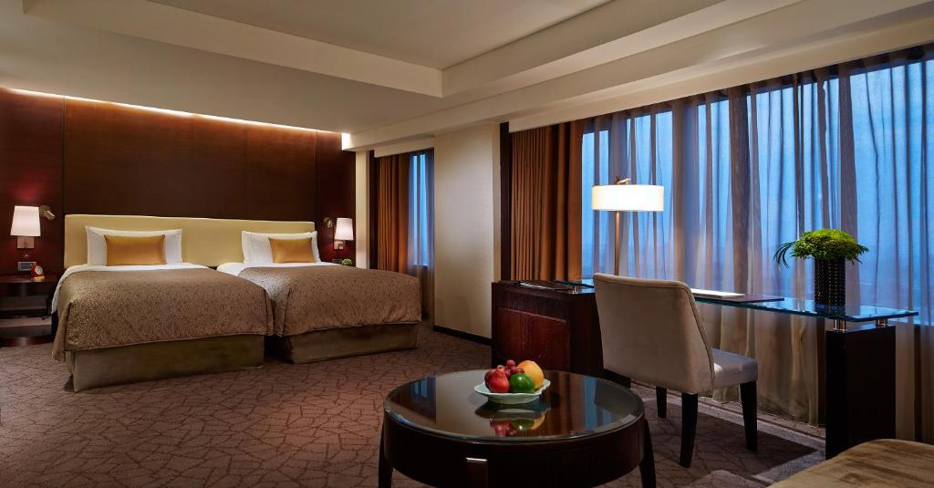 a hotel room with a bed and a desk and a table at Shangri-La Far Eastern Tainan in Tainan