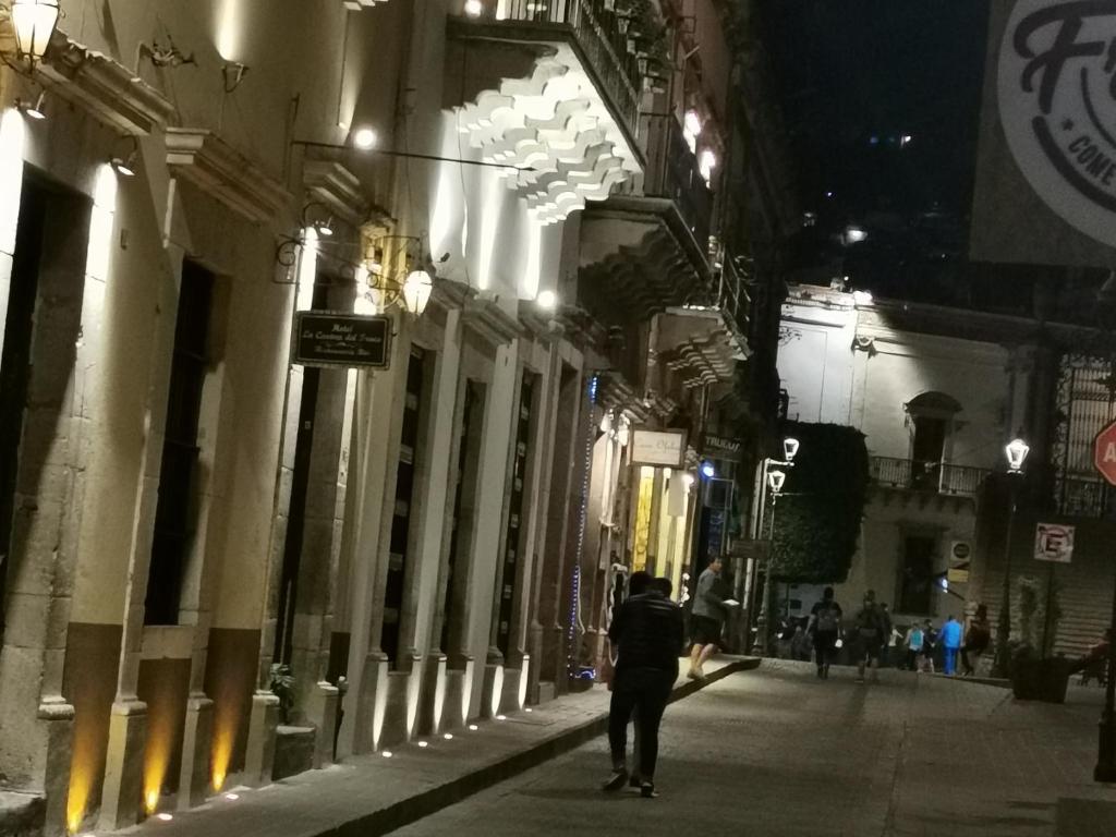 a person walking down a street at night at Hotel Casona del Truco in Guanajuato