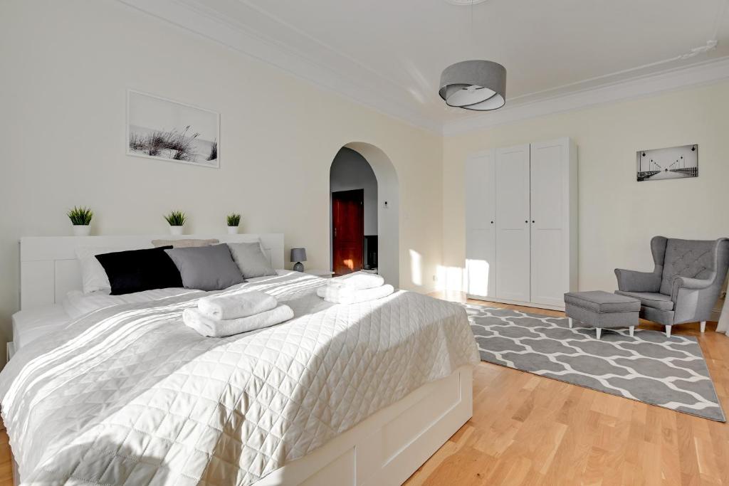 1 dormitorio blanco con 1 cama grande y 1 silla en Lion Apartments - Palermo Spacious Family Apartment 3 min walk from the beach, en Sopot