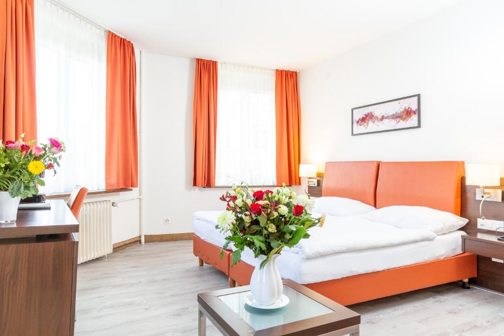 ein Hotelzimmer mit einem Bett und Blumen auf dem Tisch in der Unterkunft Hotel Rheinfelderhof in Basel