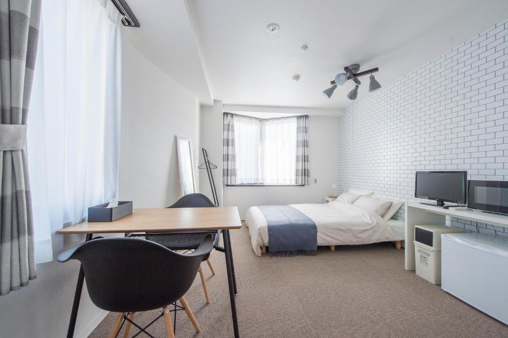 een slaapkamer met een bed en een bureau met een computer bij Syukur Ofuna in Kamakura