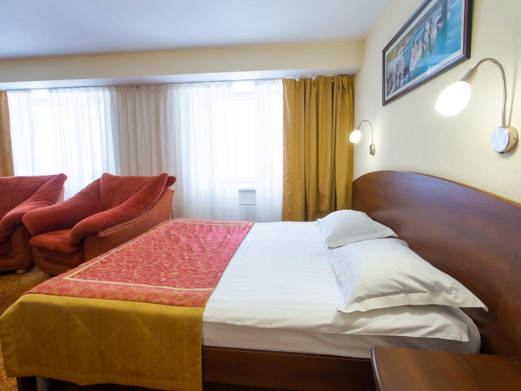 a hotel room with a bed and a chair at AZIMUT Hotel Kemerovo in Kemerovo