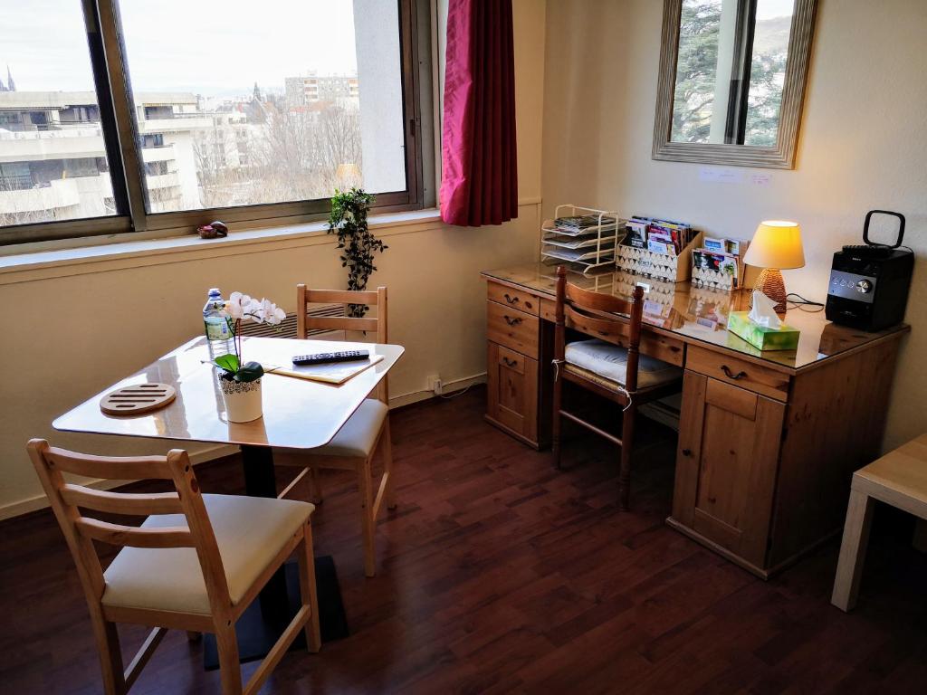 une salle à manger avec une table et un bureau avec des chaises dans l'établissement Studio "Chez Alain" avec garage sécurisé et clim, à Chamalières