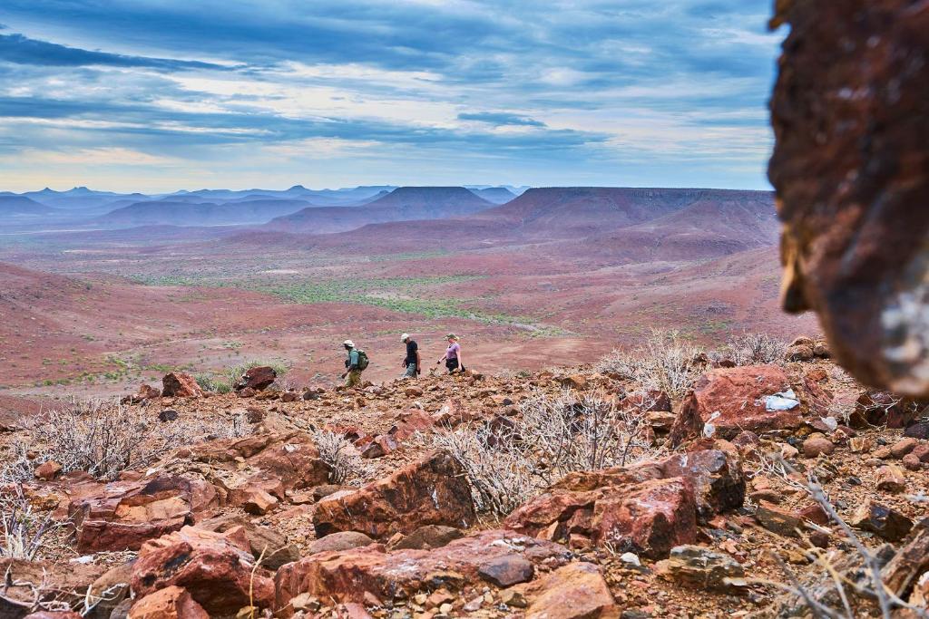 three people standing on top of a rocky mountain at Etendeka Mountain Camp in Damaraland