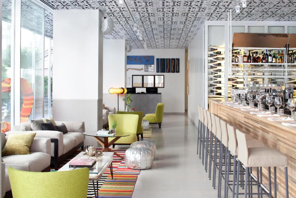 hol z krzesłami oraz bar z stojakami na wina w obiekcie Mendeli Street Hotel w Tel Awiwie