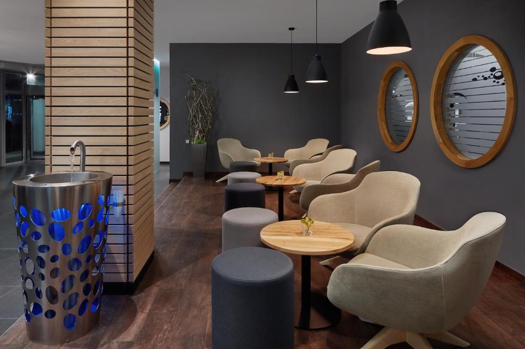 a waiting room with tables and chairs and mirrors at Spa Hotel Felicitas in Poděbrady