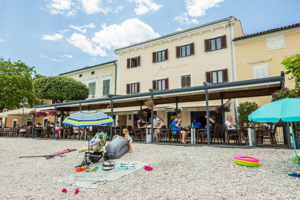 un grupo de personas sentadas en una playa frente a un edificio en Aparthotel Gimi, en Mošćenička Draga