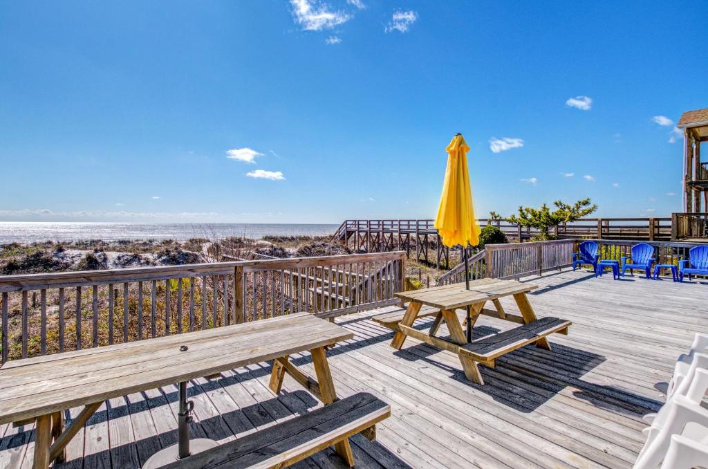 eine Terrasse mit Bänken und Sonnenschirm und der Strand in der Unterkunft Summertime in Folly Beach