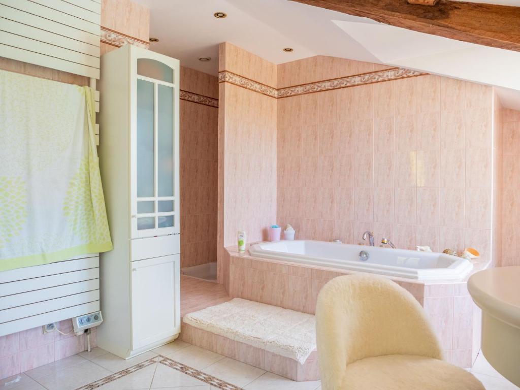 a bathroom with a tub and a chair at Château l&#39;Hubertière, classé du tourisme 4 étoiles in Bouresse