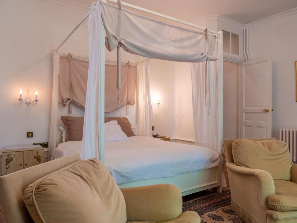 a bedroom with a canopy bed and two chairs at Château l&#39;Hubertière, classé du tourisme 4 étoiles in Bouresse