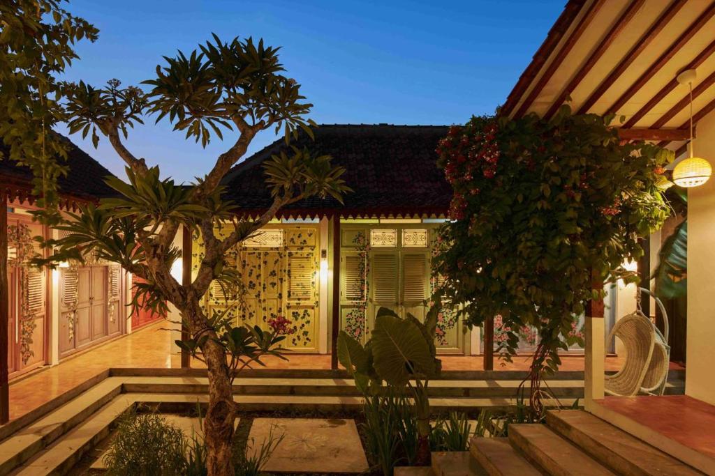 a house with a courtyard with a tree in front of it at Chendela Yogyakarta in Yogyakarta