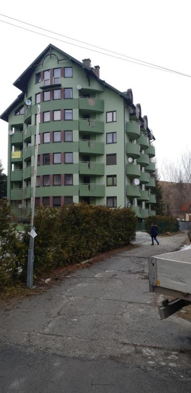 un grand bâtiment avec une personne qui marche devant lui dans l'établissement Apartamenty Krynica Zdrój, à Krynica-Zdrój