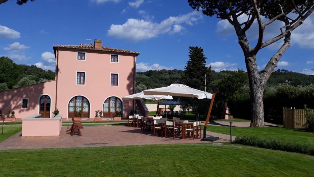 różowy budynek ze stołami i parasolami przed nim w obiekcie Moraiolo Podere le Bozze con piscina WI-FI w mieście Castagneto Carducci