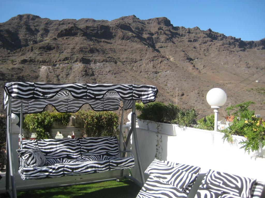 a patio with a black and white umbrella and mountains at Apartment Casa Molino in Mogán