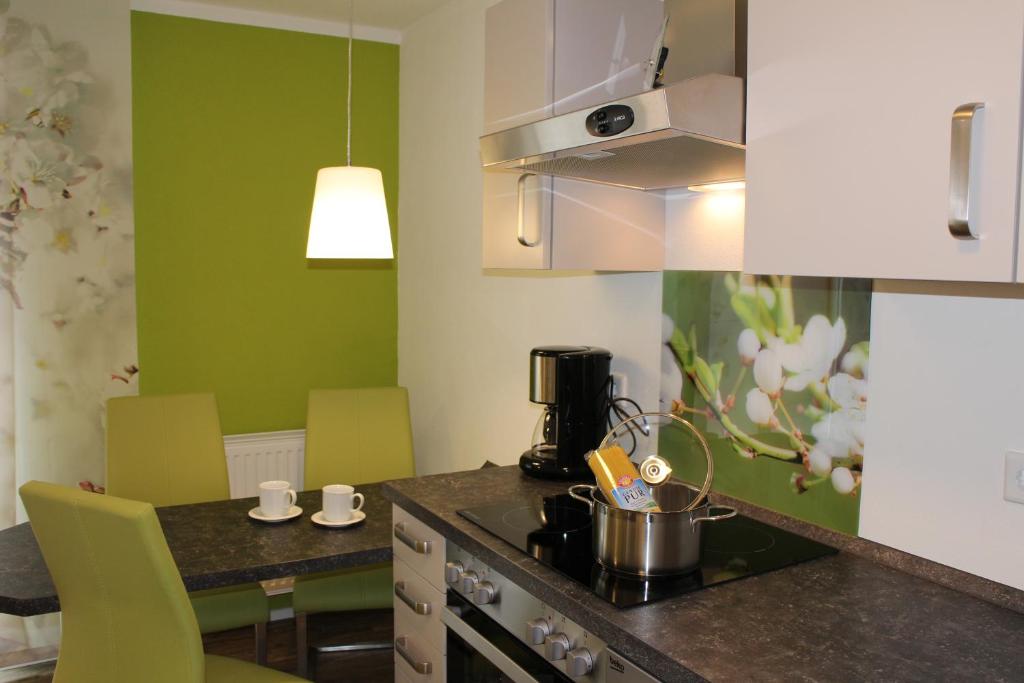 a kitchen with green walls and a table with chairs at Kaiser Wilhelm - Appartement mit Saunanutzung in Burgbernheim