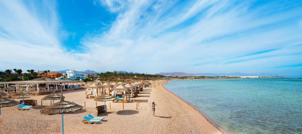 a beach with chairs and umbrellas and the water at Amwaj Oyoun Resort & Casino in Sharm El Sheikh