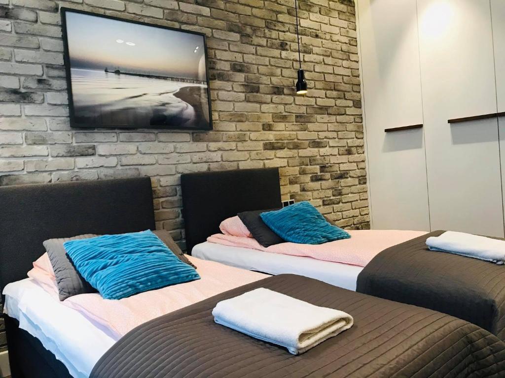 two beds in a room with a tv on a brick wall at Victus Apartamenty, Apartament Omega in Sopot