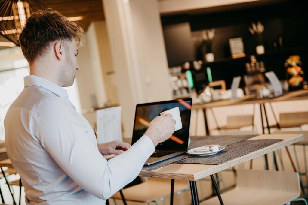 a man sitting at a table using a laptop computer at Airbase Hotel in Kalsdorf bei Graz