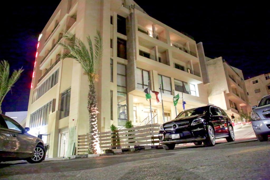 a large building with cars parked in front of it at Lijam Hotel in Amman