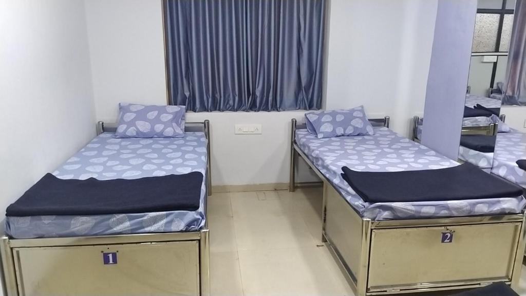two beds in a room with blue and white sheets at Shiv Sai Dormitory in Vadodara