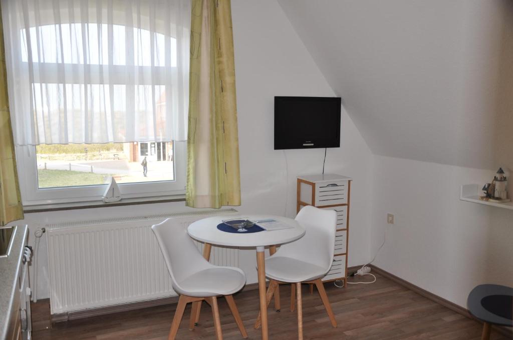 een kamer met een tafel en twee stoelen en een televisie bij Seevilla Wietjes Whg 6 in Baltrum