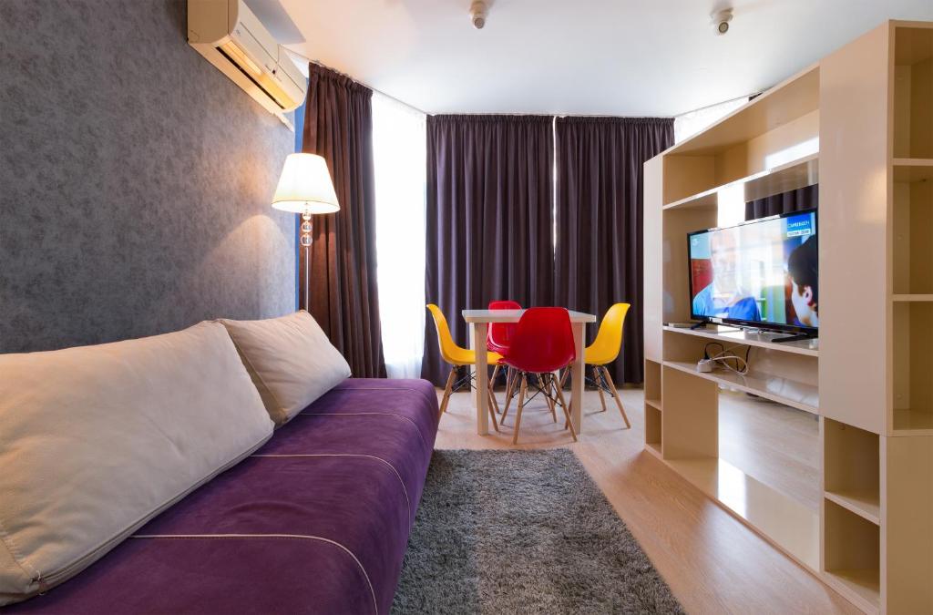 a hotel room with a couch and a table with chairs at The Perfect One-Bedroom Maisonette in Plovdiv in Plovdiv