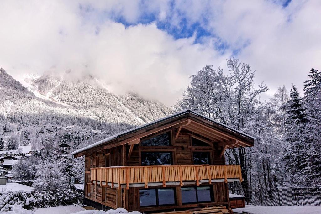 ein Blockhaus mit schneebedeckten Bergen im Hintergrund in der Unterkunft Chalet des Amis- Chamonix All Year in Chamonix-Mont-Blanc