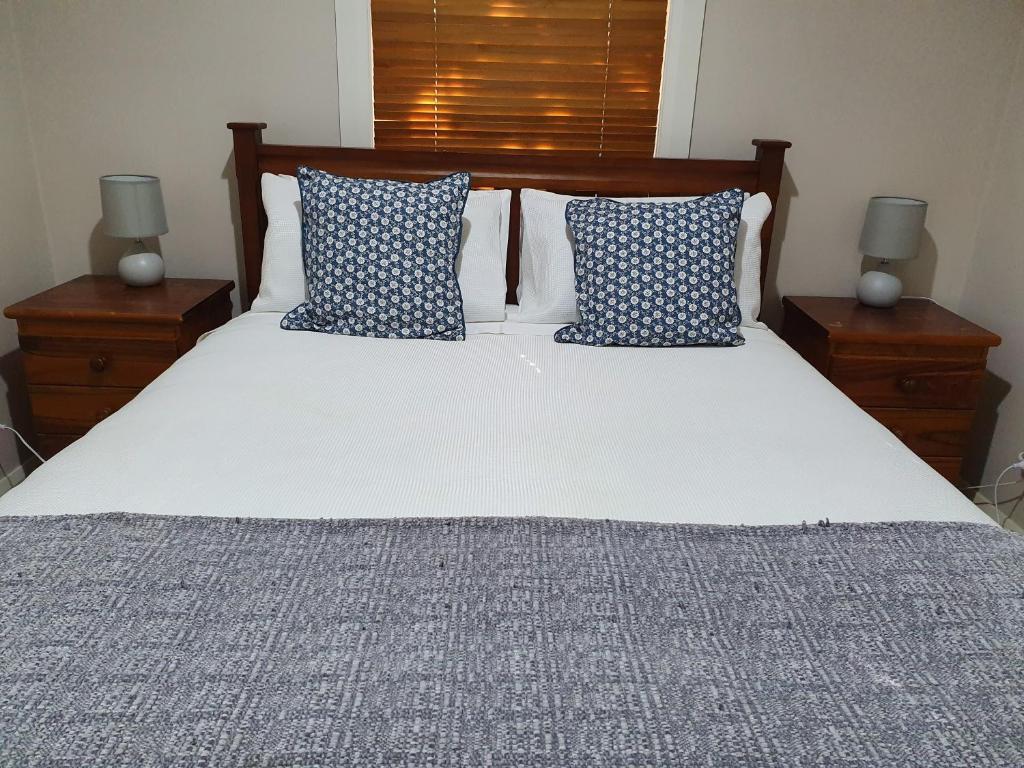 a bedroom with a bed with blue and white pillows at Denison Lodge in Mudgee