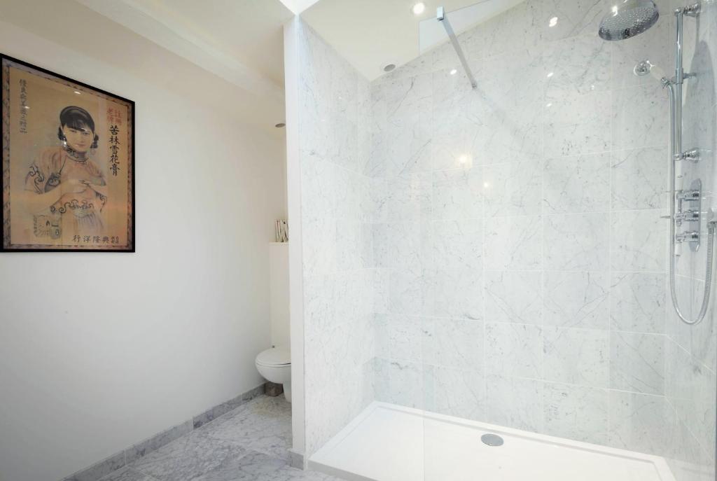 La salle de bains blanche est pourvue d&#39;une douche et de toilettes. dans l&#39;établissement Villa Segur, à Bordeaux