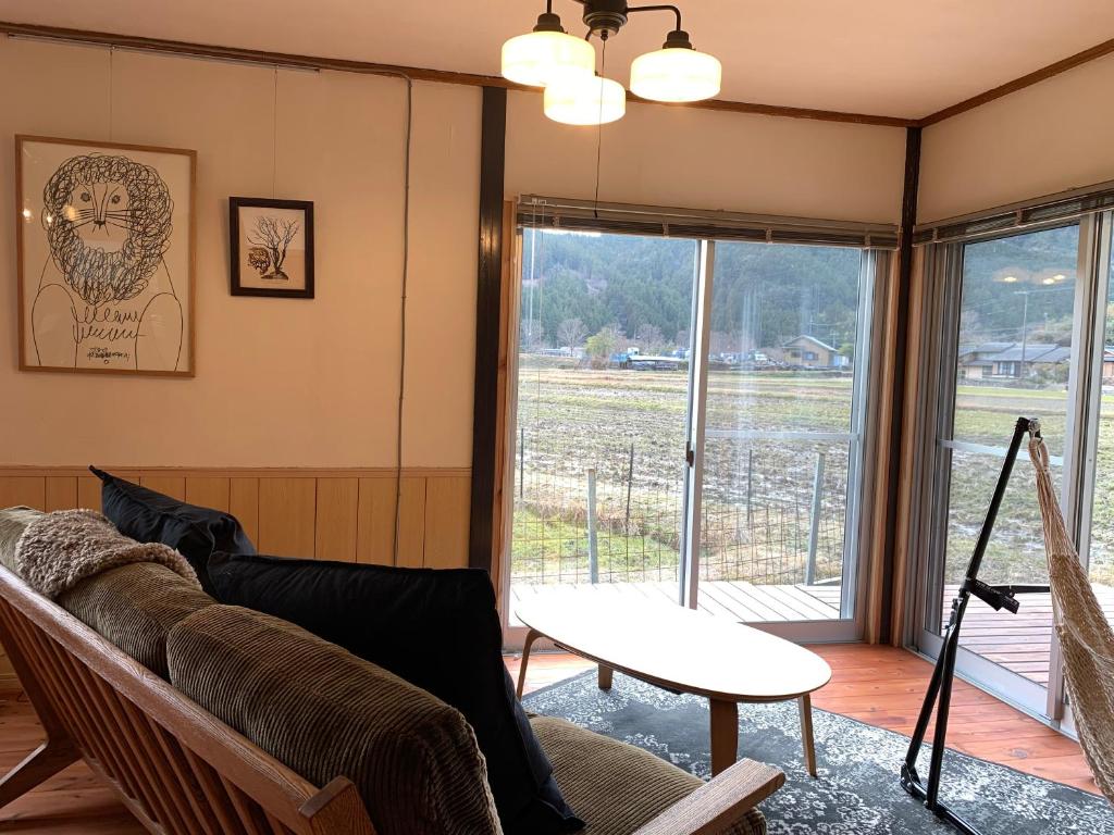een woonkamer met een bank en een raam bij Private house Kumanoyasai BASE in Tanabe