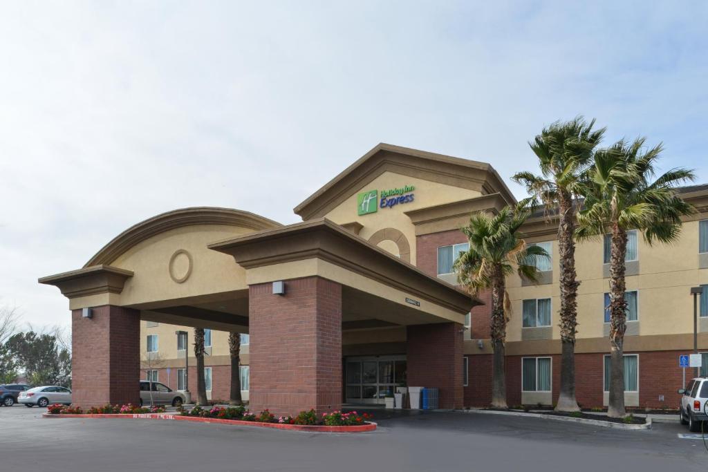 a hotel building with palm trees in a parking lot at Holiday Inn Express Woodland, an IHG Hotel in Woodland