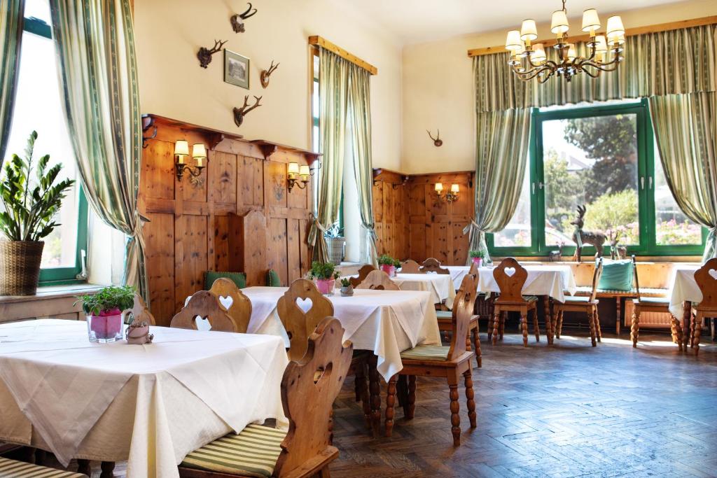 restauracja z białymi stołami, krzesłami i oknami w obiekcie Hotel Bergwirt Schönbrunn w Wiedniu