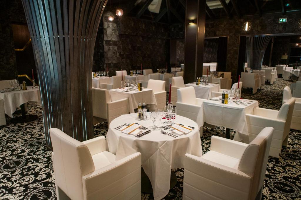 a dining room with white tables and white chairs at Le Grand Hôtel Le Touquet-Paris-Plage in Le Touquet-Paris-Plage