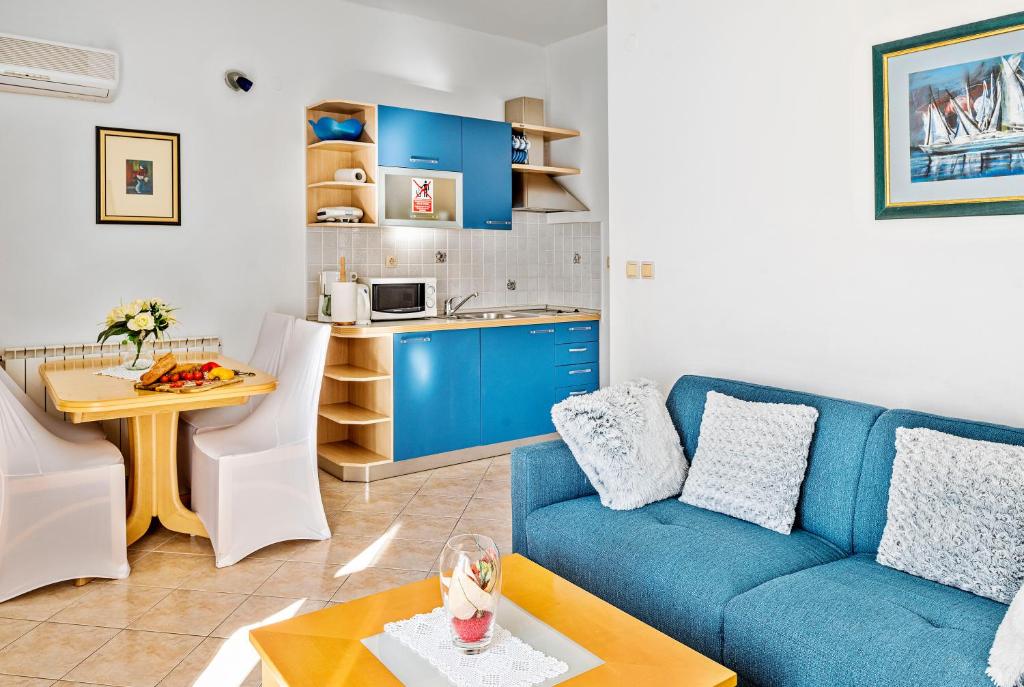 sala de estar con sofá azul y cocina en Apartmani Barun en Šibenik