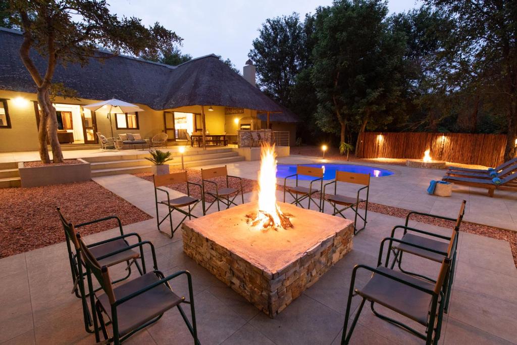 a patio with a fire pit and chairs and a pool at Kingly Bush Villa in Phalaborwa