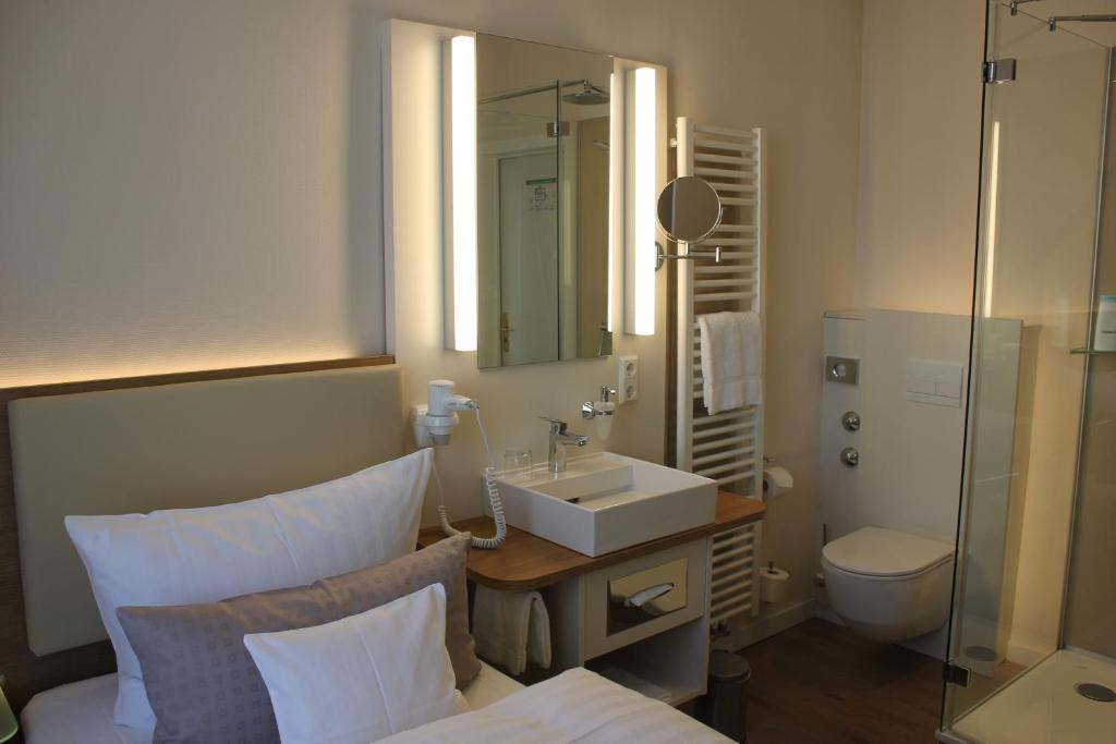 a bathroom with a sink and a toilet and a mirror at Stüttgens Hotel in Velbert