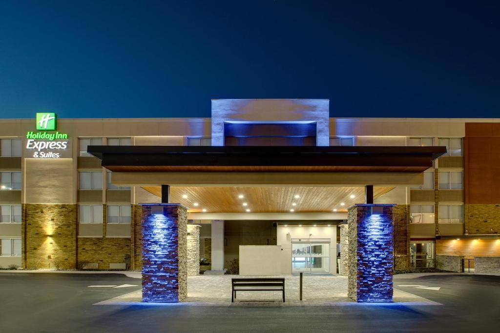 um edifício de hotel com um banco em frente em Holiday Inn Express & Suites Wapakoneta, an IHG Hotel em Wapakoneta