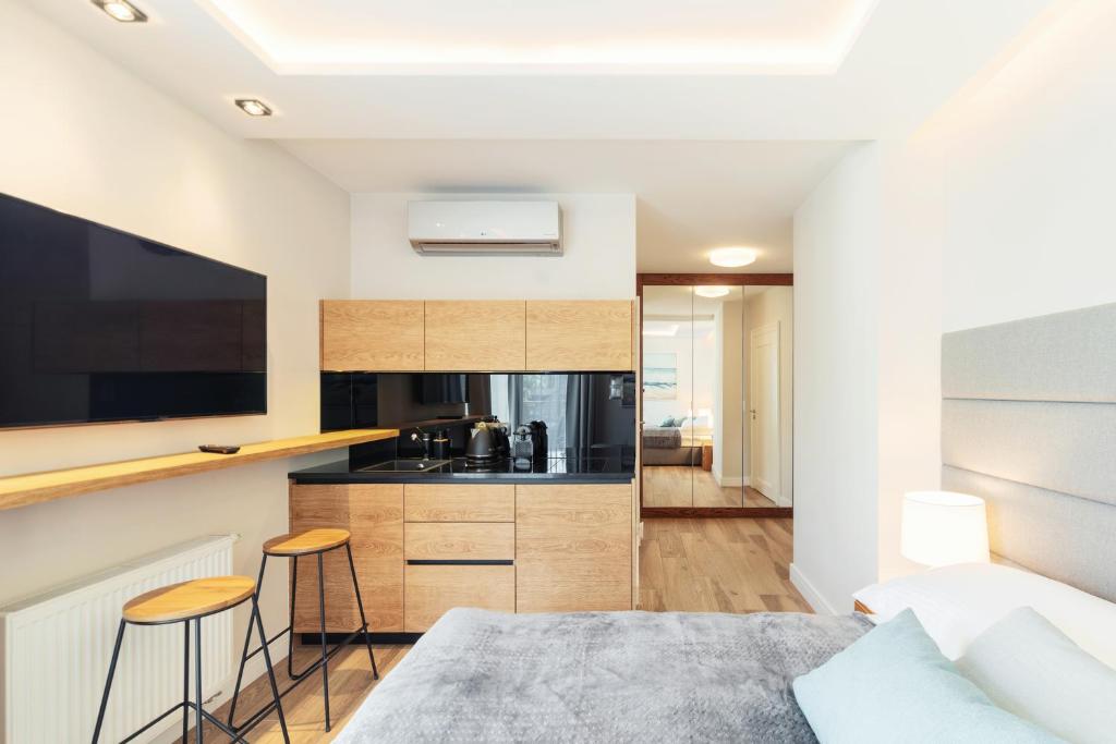 ein Schlafzimmer mit einem Bett und eine Küche mit einer Theke in der Unterkunft Studio with terrace in a luxury closed estate by Grand Apartments in Sopot