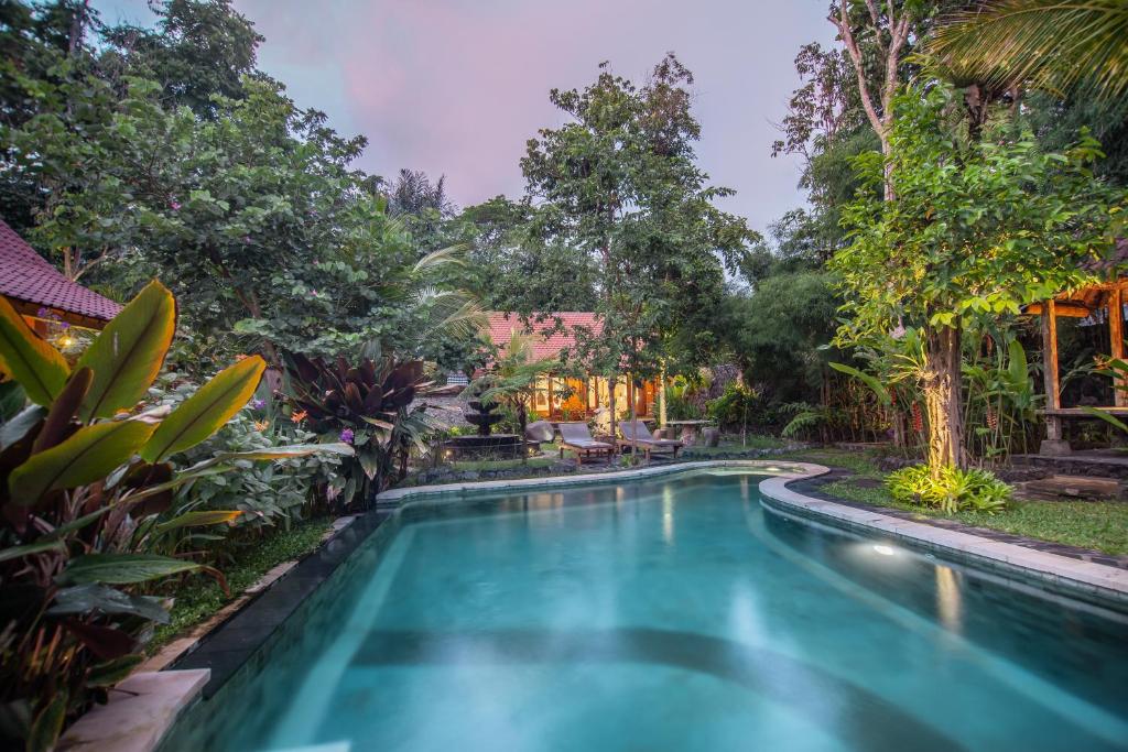 a swimming pool in a garden with trees at Jero Sebali Villa in Ubud