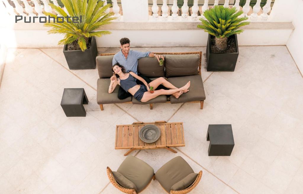 a man and woman sitting on a couch in a living room at Puro Hotel Oasis Urbano in Palma de Mallorca