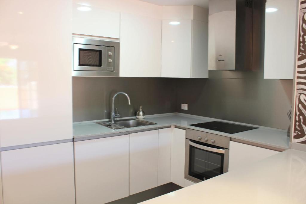 eine Küche mit weißen Schränken und einer Spüle und einer Mikrowelle in der Unterkunft Perfecto apartamento de playa in Callao Salvaje