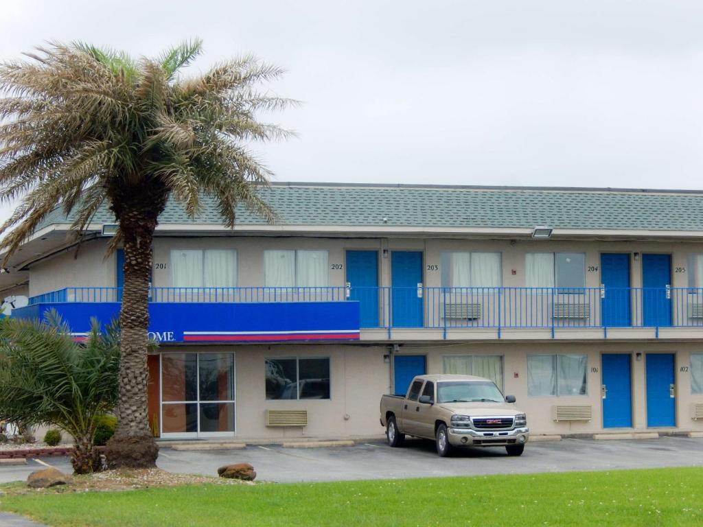 un camión estacionado frente a un edificio con una palmera en Motel 6-Clute, TX, en Clute