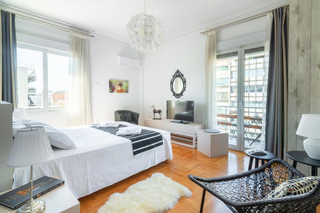 een witte slaapkamer met een bed en een tafel en stoelen bij Zeus by Heloni Apartments in Athene