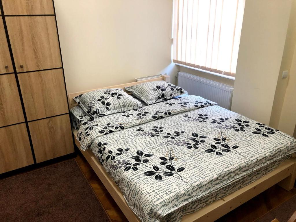 Schlafzimmer mit einem Bett mit einer schwarzen und weißen Bettdecke in der Unterkunft GIL apartments, Korzo 7,2 centre in Uschhorod