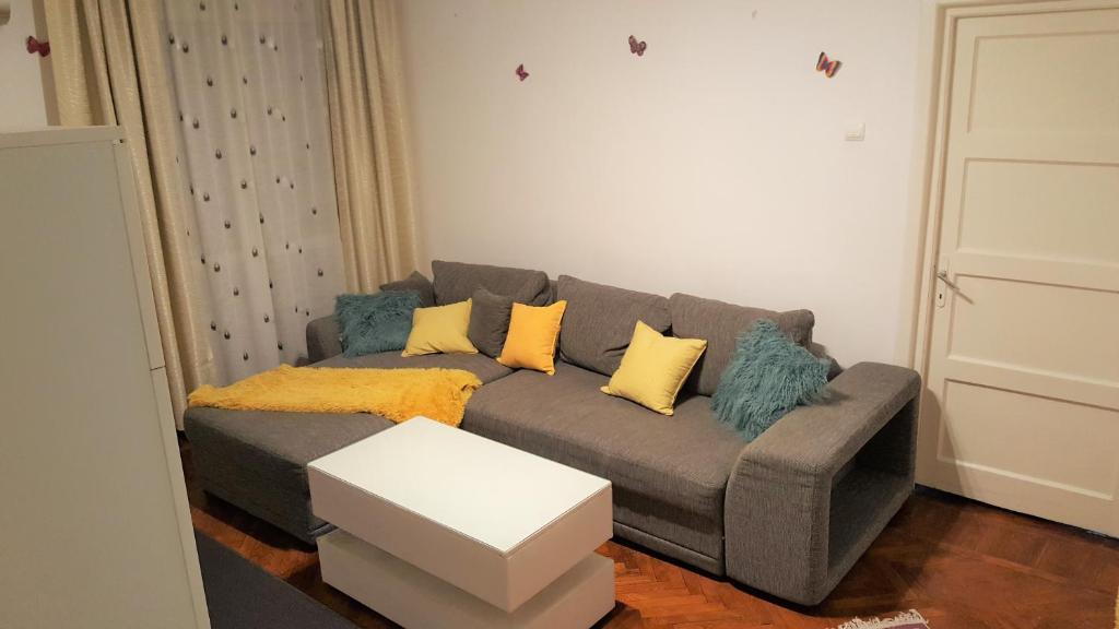 a living room with a gray couch with yellow pillows at Venus Plaza Apartment Ploiesti in Ploieşti