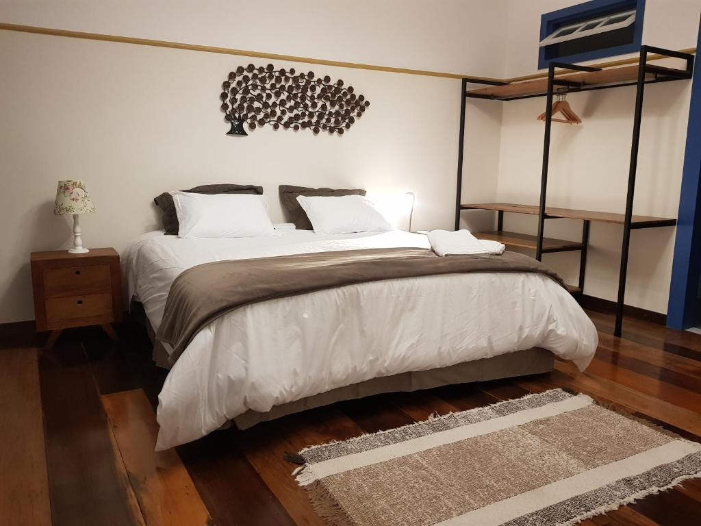 una camera da letto con un grande letto con cuscini bianchi di Suite Família Inconfidentes a Ouro Preto