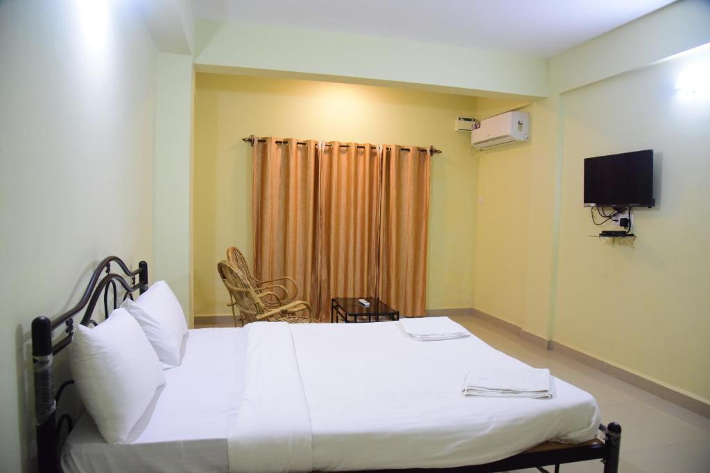 a bedroom with a white bed and a television at Homestay Siolim in Siolim